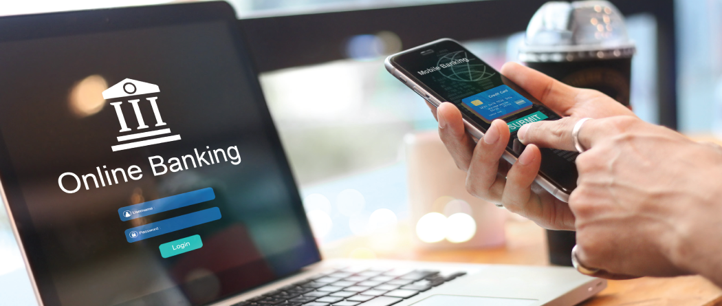 laptop with online banking and hands holding a phone with mobile banking