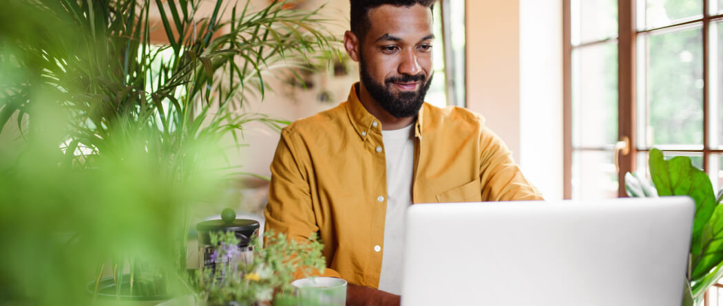 Man surrounded by plants using a laptop