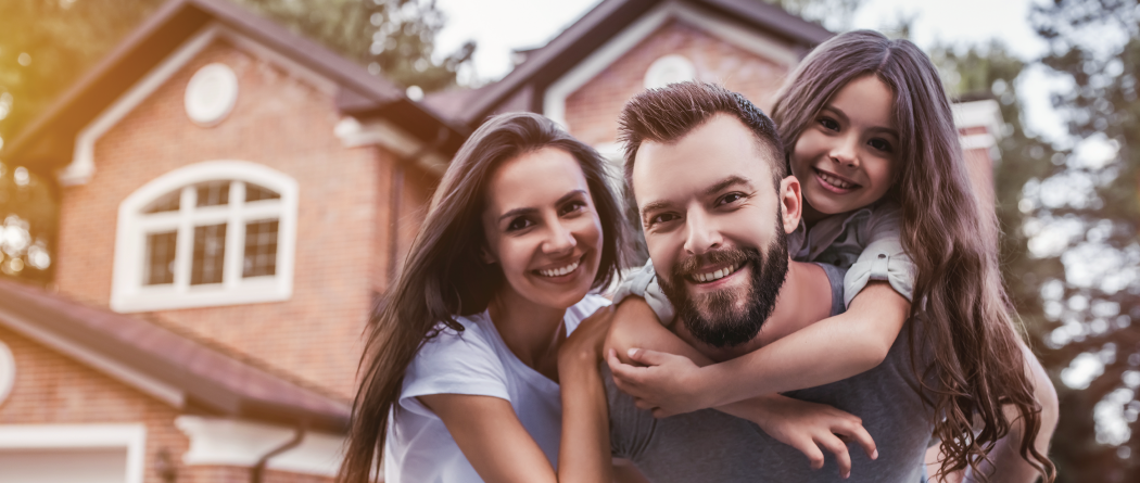 family of three playing outside of new home