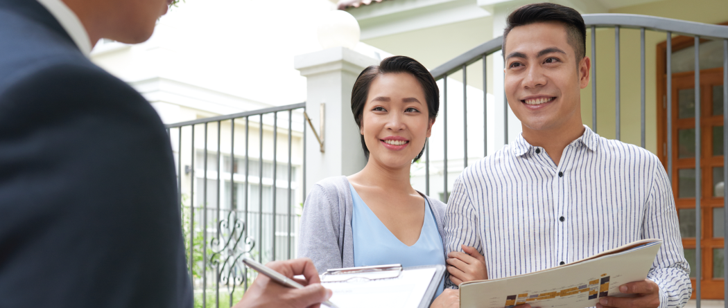 couple signing mortgage docs outside home they just purchased