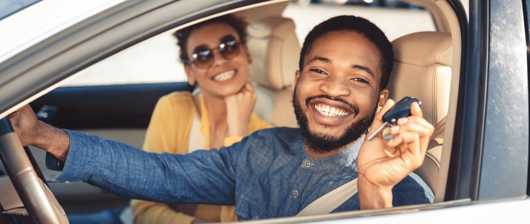 couple in front seats of new car, driver holding the keys