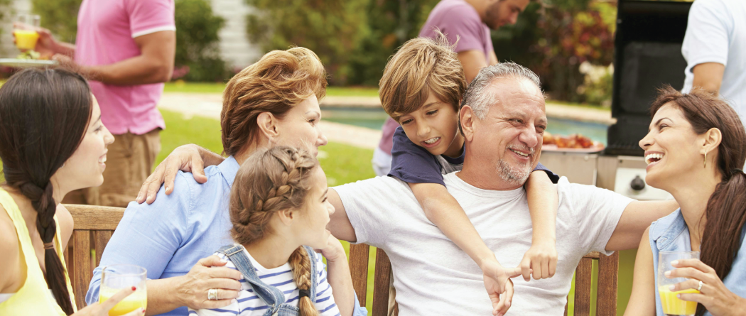 family gathering around grandfather at dinner table outside