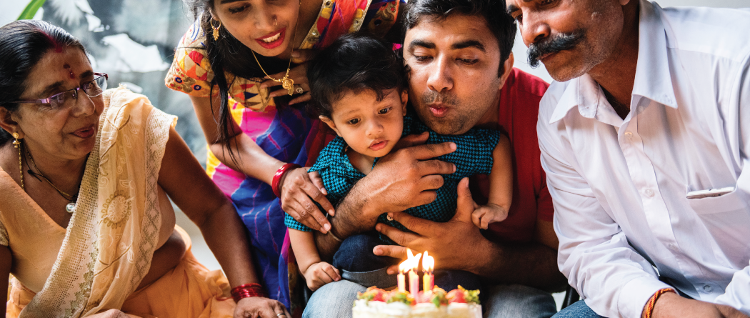 three generations of family blowing out birthday candles