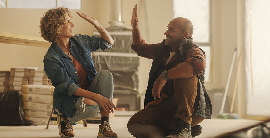 Two people high-fiving in a room that is midway through a renovation.