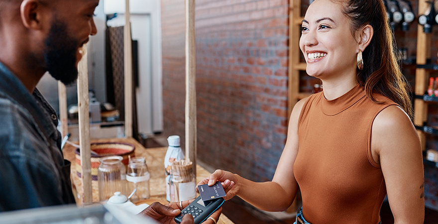 A customer paying with a card at a card reader on a shop counter.