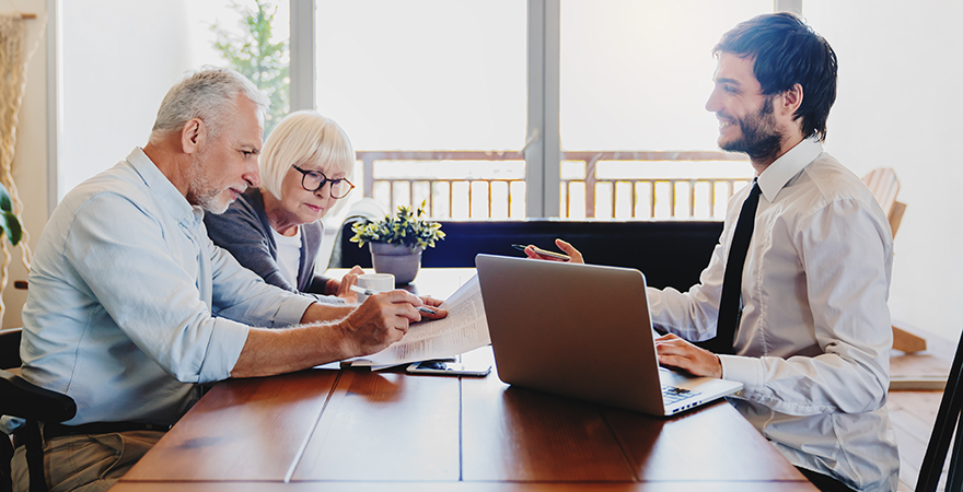 An older couple meeting with an advisor across a desk.