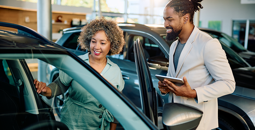 A salesperson showing a car to a customer at a dealership.