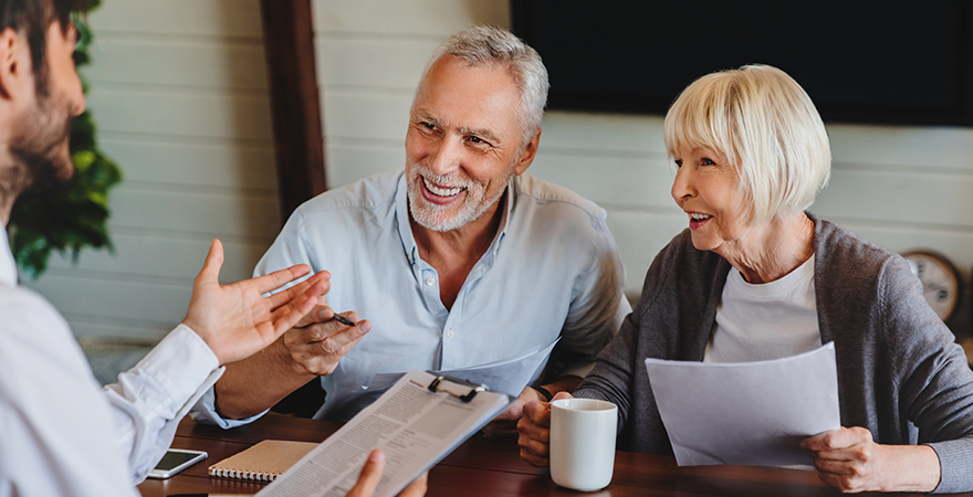 An older couple reviewing documents with an advisor at a table.