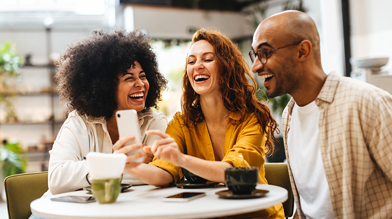 3 people laughing sitting at a table