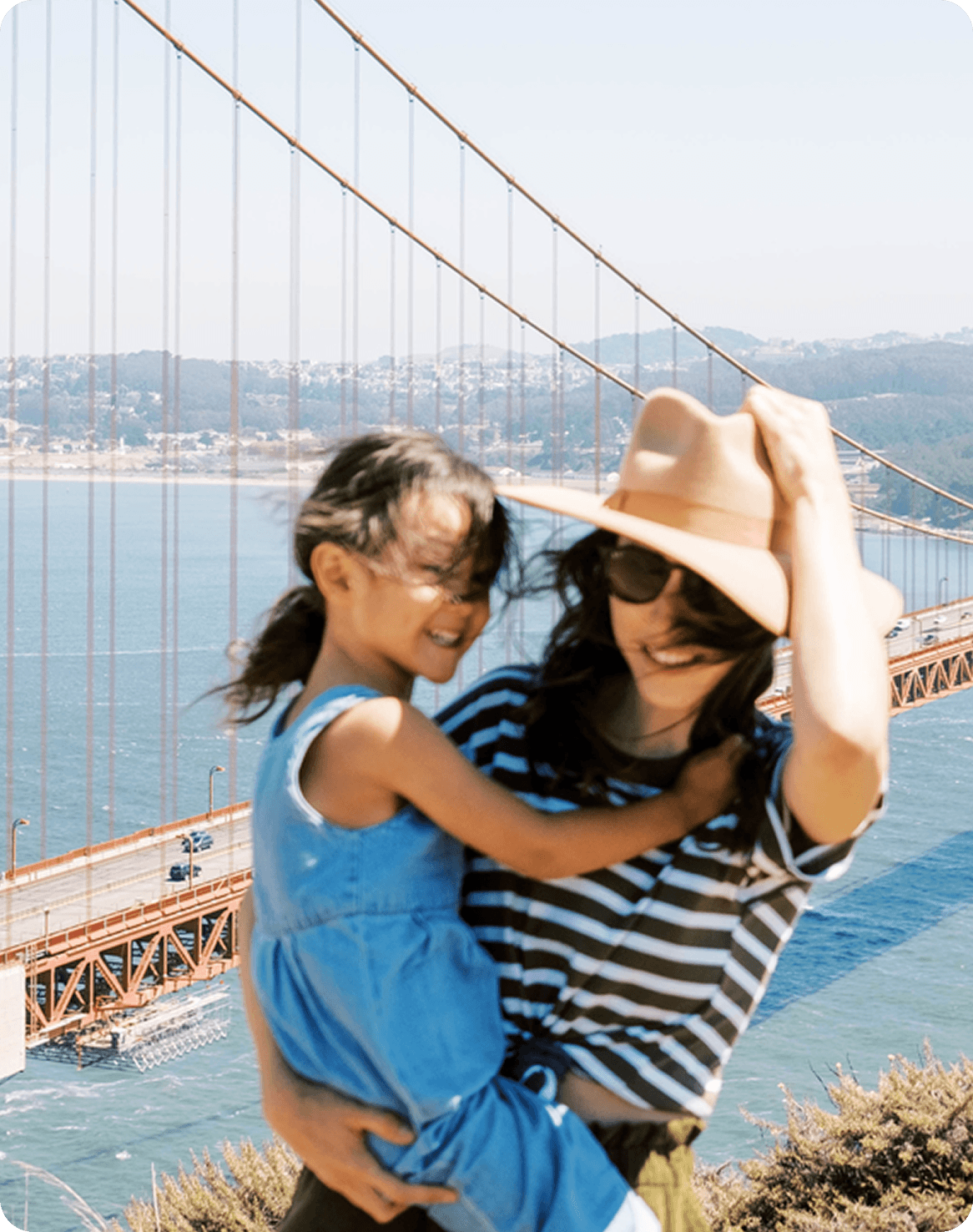 Mother holds child in front of golden gate bridge