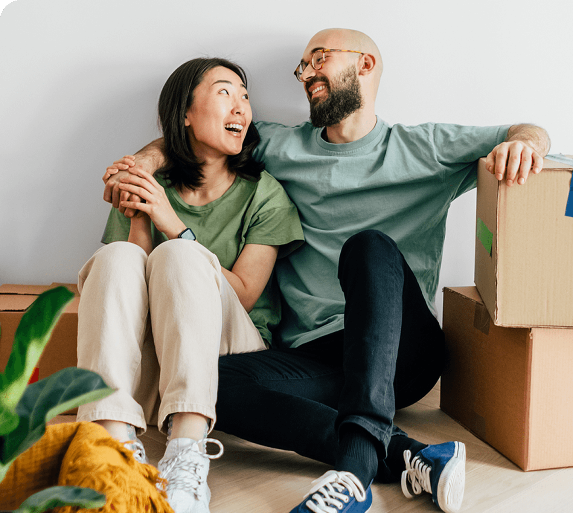 Couple sitting down next to moving boxes smiling