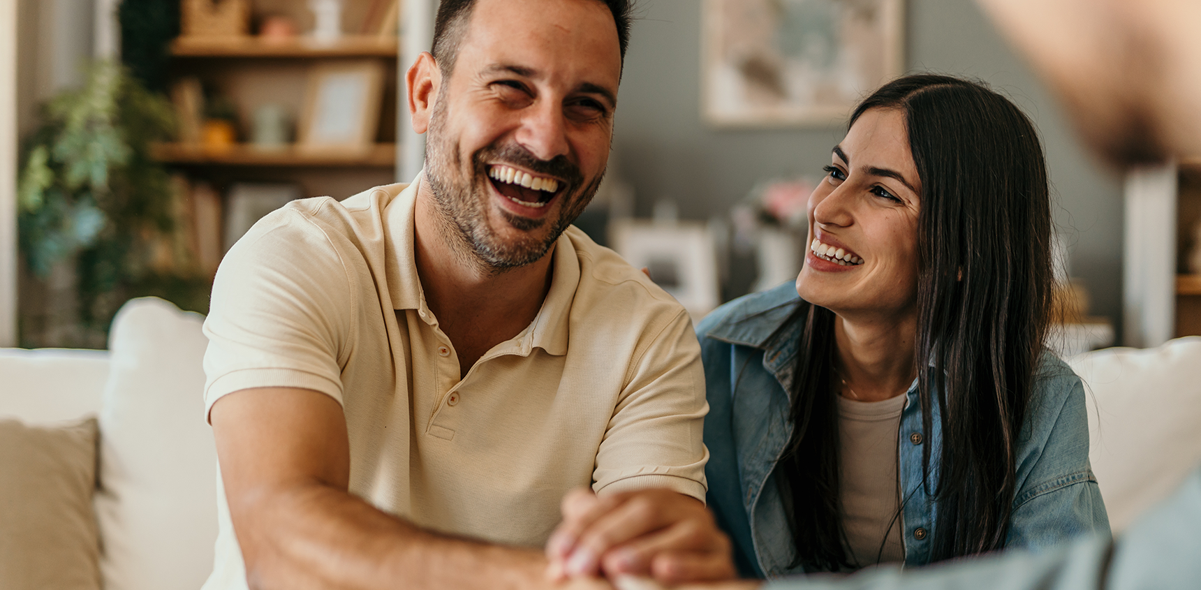 Couple sitting on couch shaking hands of financial advisor